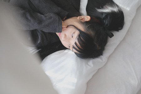 Young pretty girl wearing black cotton sweatshirt on bedroom white toneの写真素材