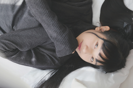 Young pretty girl wearing black cotton sweatshirt on bedroom white toneの写真素材