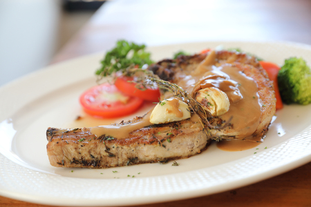 grilled pork chop with vegetable on dish with wood table backgroundの写真素材