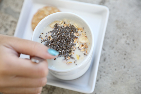 Cereal on milk in cup with woman hand breakfastの写真素材
