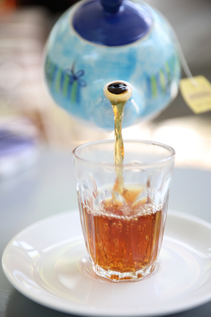 pour tea pot on tea cup on wood table backgroundの写真素材