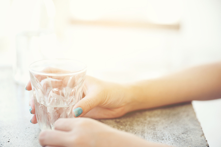 water in glass with woman hand and bottle on table in coffee shopの写真素材
