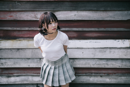 portrait of asian girl with white shirt and skirt looking in outdoor nature vintage film styleの写真素材