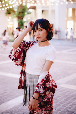 portrait of asian girl with white shirt and skirt looking in outdoor urban vintage film styleの写真素材