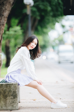 portrait of asian girl with white shirt and skirt sitting relax n outdoor nature vintage film styleの写真素材