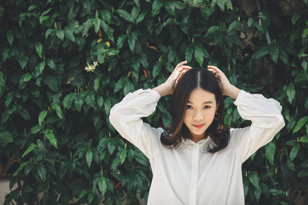portrait of asian girl with white shirt and skirt looking in outdoor nature vintage film styleの写真素材