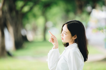portrait of asian girl with white shirt and skirt pointing in outdoor nature vintage film styleの写真素材
