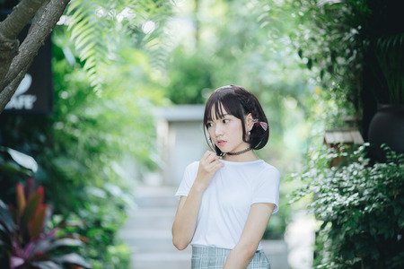 portrait of asian girl with white shirt and skirt looking in outdoor nature vintage film styleの写真素材