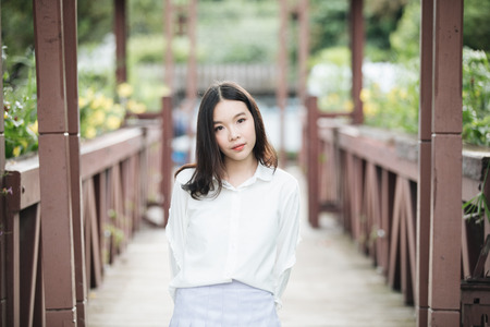 portrait of asian girl with white shirt and skirt looking in outdoor nature vintage film styleの写真素材