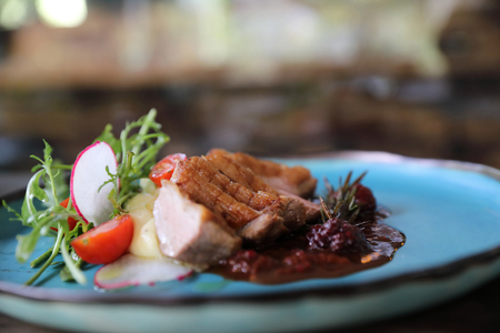 Duck confit with salad , baked apple and raspberry sauce served on wooden tableの写真素材