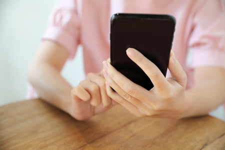 Female hand with smartphone trading stock online in coffee shop , Business conceptの写真素材