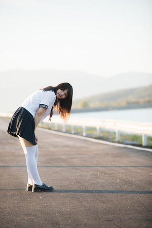 Portrait of Japanese school girl uniform smile with walkway and riverの写真素材