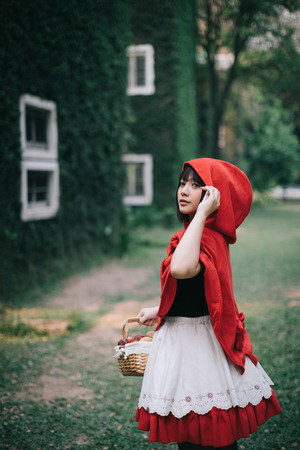 Portrait young woman with  Red  Hood costume in green tree parkの写真素材