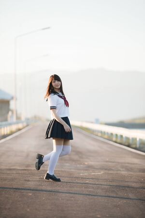 Portrait of Japanese school girl uniform smile with walkway and riverの写真素材