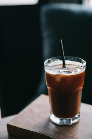 Iced coffee in a tall glass on wood at coffee shopの写真素材