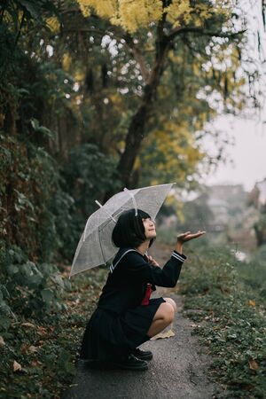 Portrait of Asian school girl walking with umbrella at  nature walkway on rainingの写真素材