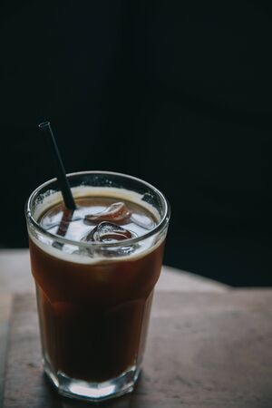 Iced coffee in a tall glass on wood at coffee shop