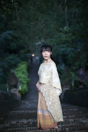 Portrait of Thai female with traditional Thai dress with temple background