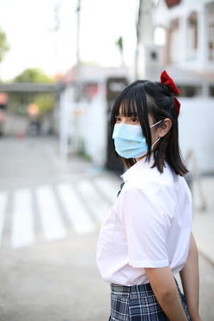 Asian school girl with mask in urban city on tree backgroundの写真素材