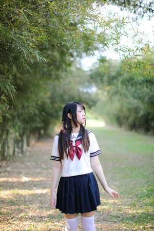 Portrait of beautiful Asian japanese high school girl uniform looking with bamboo forest background