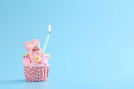 Colorful cupcakes with candle isolated in blue backgroundの写真素材
