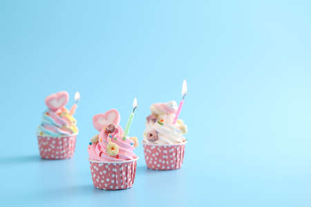 Colorful cupcakes with candle isolated in blue backgroundの写真素材