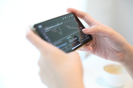 Female hand with smartphone trading stock online in coffee shop , Business conceptの写真素材