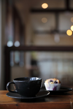 Coffee cup with muffin on wood table in local coffee shopの写真素材