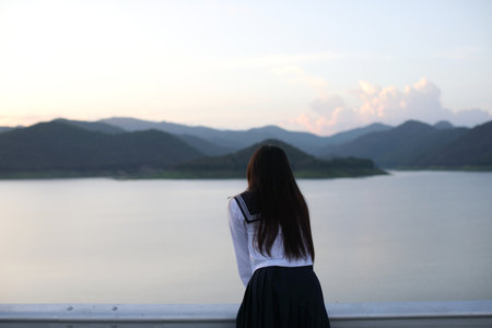Asian school girl looking mountain with river in sunriseの写真素材