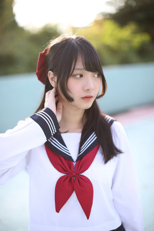 Portrait of Asian schoolgirl looking with blue stadium backgroundの写真素材
