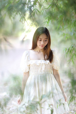 Beautiful young woman with white dress on garden backgroundの写真素材