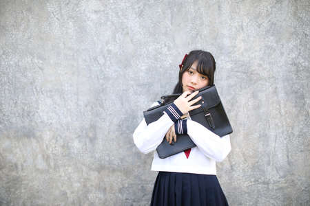 Portrait of Asian schoolgirl with grey backgroundの写真素材