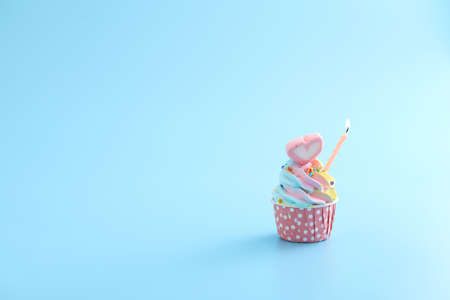 Colorful cupcake with candle isolated in blue backgroundの写真素材