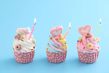 Colorful cupcakes with candle isolated in blue backgroundの写真素材
