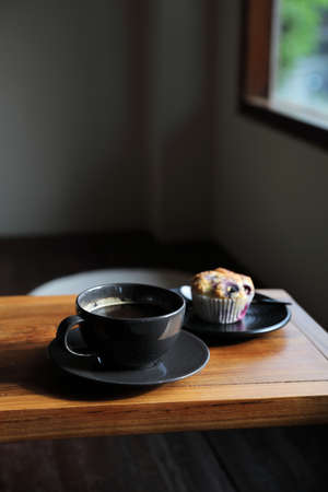 Coffee cup with muffin on wood table in local coffee shopの写真素材