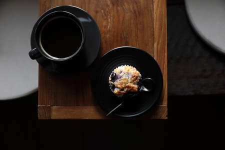 Coffee cup with muffin on wood table in local coffee shopの写真素材