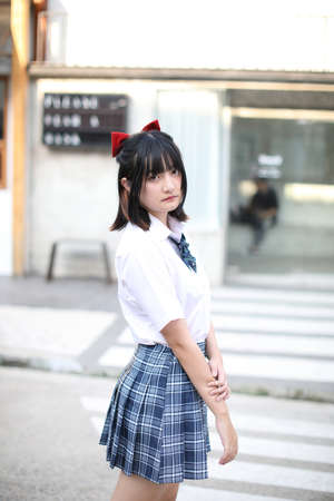 Asian school girl walking and looking at urban cityの写真素材