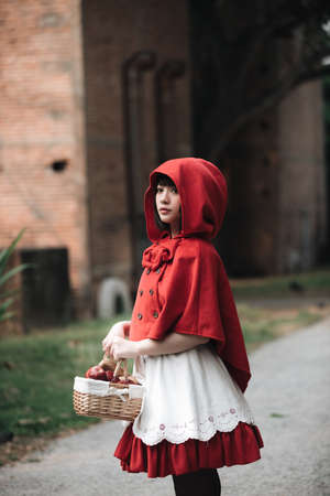 Portrait young woman with Little Red Riding Hood costume in green tree parkの写真素材