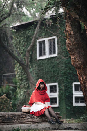 Portrait young woman with Little Red Riding Hood costume in green tree parkの写真素材