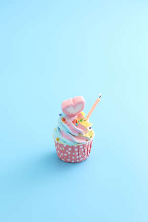 Colorful cupcake with candle isolated in blue background