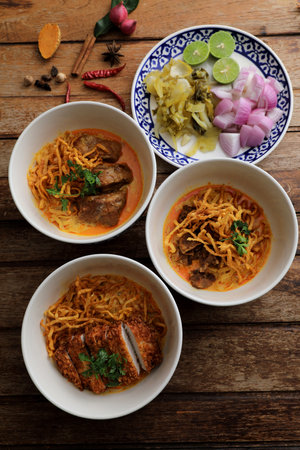 Local northern Thai food Egg noodle curry with pork and beef on wood backgroundの写真素材