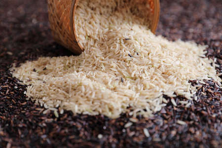 Organic raw brown rice and riceberry rice on Wicker basket in close up