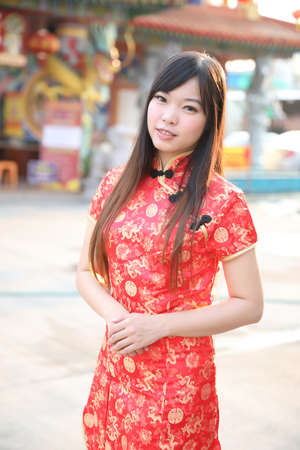 beauty woman wear red cheongsam looking and smile in chinese new year