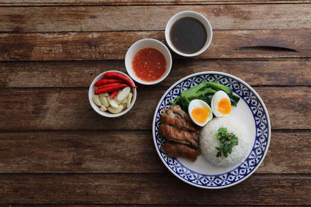 Local Thai food stewed pork leg on rice isolated in wood backgroundの写真素材