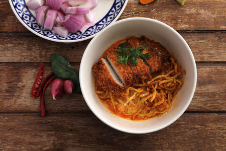 Local northern Thai food Egg noodle curry with fried pork on wood backgroundの写真素材