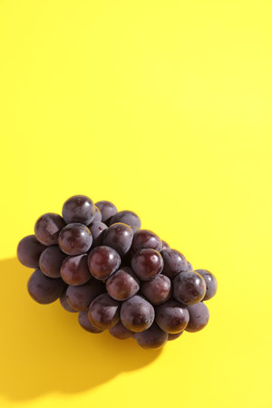 Red grapes isolated in yellow backgroundの写真素材