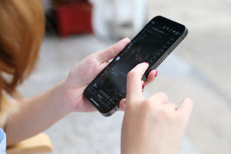 Female hand with smartphone trading stocks online in coffee shop Business conceptの写真素材