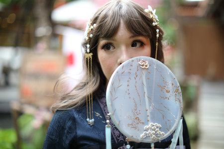 Beautiful young woman with dark blue Chinese lolita dress with Chinese gardenの写真素材