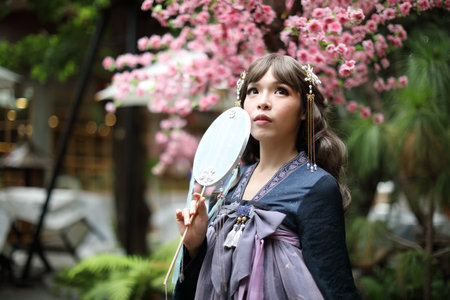 Beautiful young woman with dark blue Chinese lolita dress with Chinese gardenの写真素材