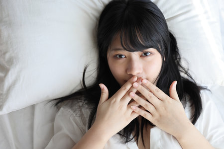 Beautiful young woman waking up in the morning at white bedroomの写真素材
